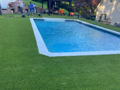 Artificial grass around backyard swimming pool by American Syn-Turf, Toccoa Georgia - low-maintenance, lush green synthetic turf for poolside landscaping